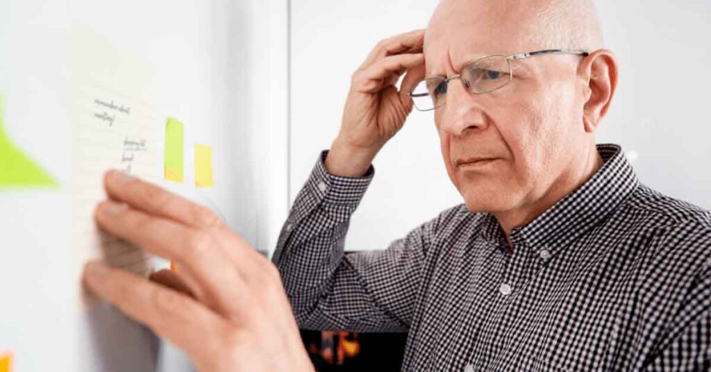 Older man looking puzzled at reminder notes he left himself